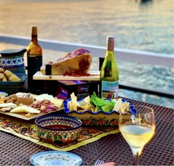 Dinner table set by the water with local dishes and wine